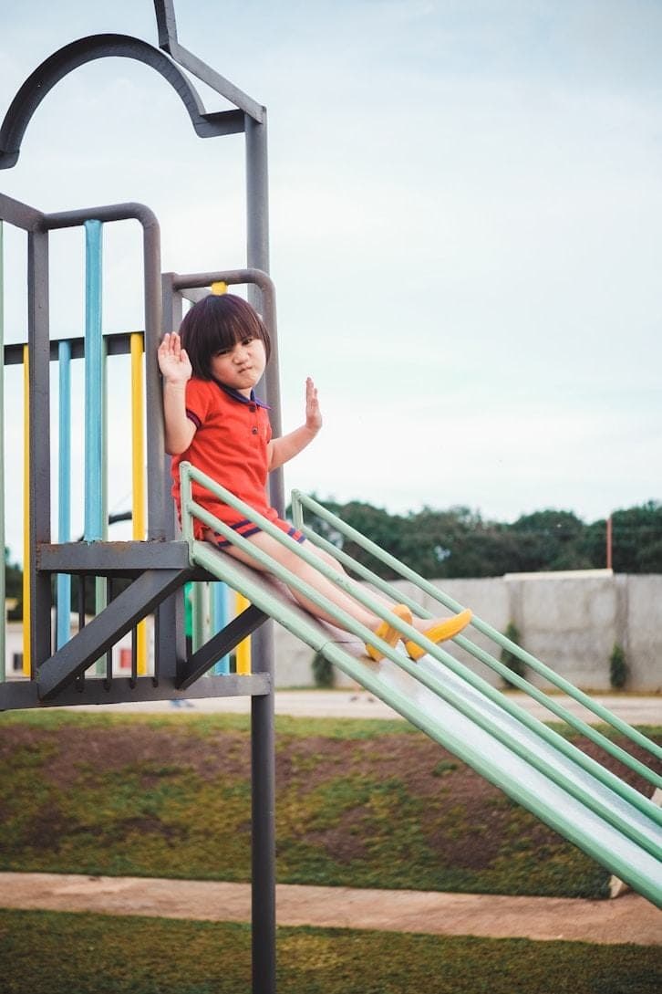 A young child riding down a curved playground slide.